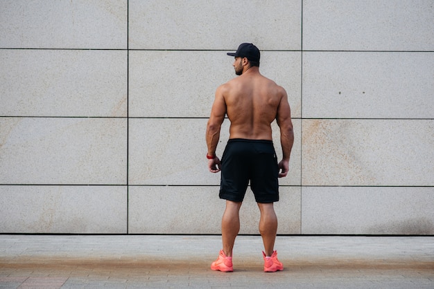 Sexy athlete stands with his back against the wall. Fitness. Healthy lifestyle.