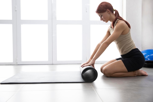 Sexy beautiful sportswoman girl unrolls a fitness mat Place for text Yoga Gymnastics