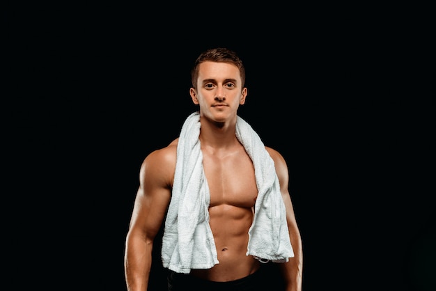 Sexy bodybuilder with muscular torso and towel isolated on black