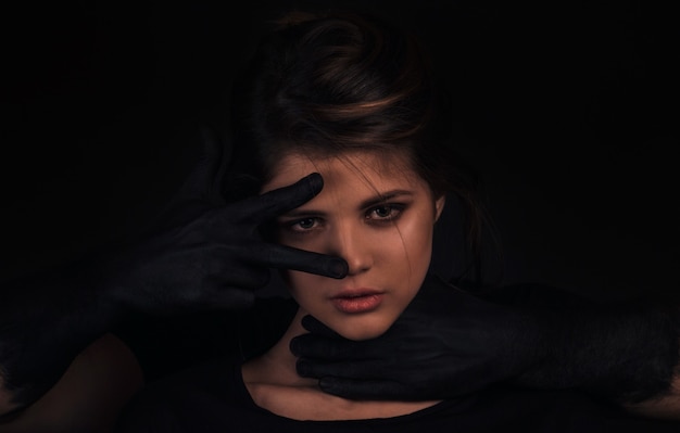 Sexy couple posing on dark cyclorama, guy with black hands hugs a beautiful girl