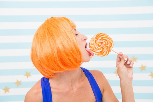 Sexy crazy girl lick lollipop. desire. crazy girl love lollipop. sexy girl eating candy. just one kiss. true desire. woman with crazy look having orange hair. perfect view.