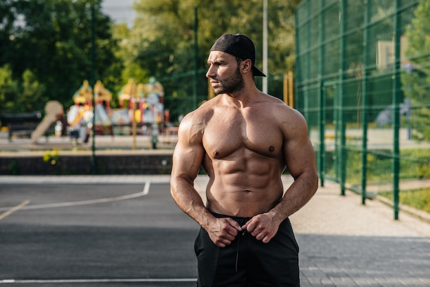 Sexy fitness sportsman posing on a sports field topless. Fitness, bodybuilding, healthy lifestyle.