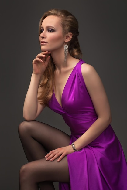 Sexy girl in evening dress posing over dark background