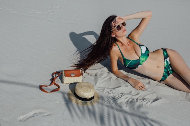 Sexy girl in the sand in a white bikini