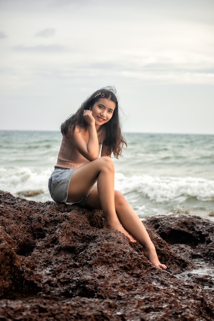 Sexy girl in a sitting on the rocks on the shore of the sea.