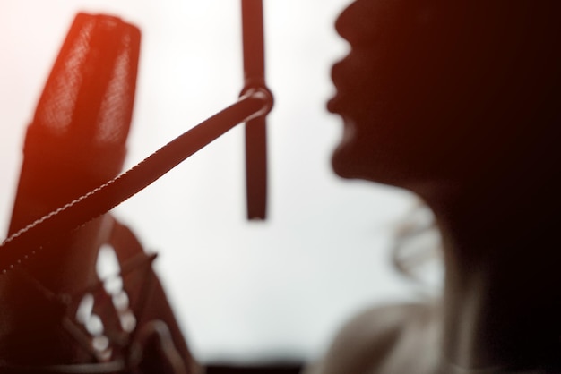 Sexy silhouette female profile with pretty face and bare shoulder near microphone on studio background Side view portrait of woman singing to microphone Closeup