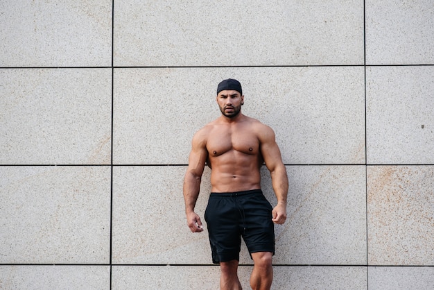 Sexy sportsman stands topless near the wall. Fitness, bodybuilding.