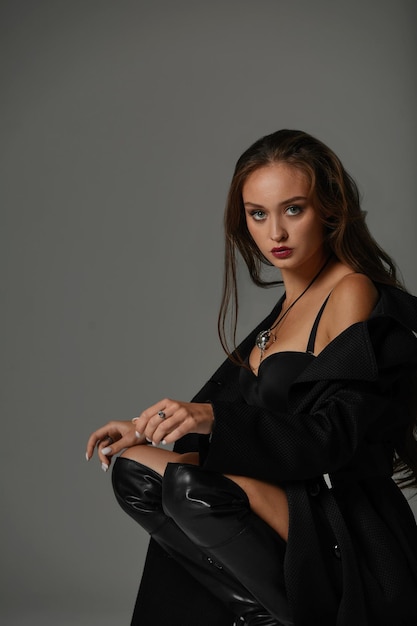 Sexy woman in black swimsuit and black high boots Fashion young woman with long legs posing at studio