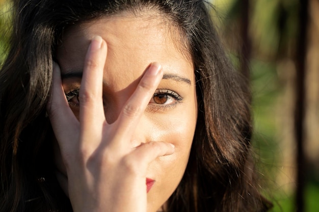 Sexy woman looks through one hand eye directed to the camera