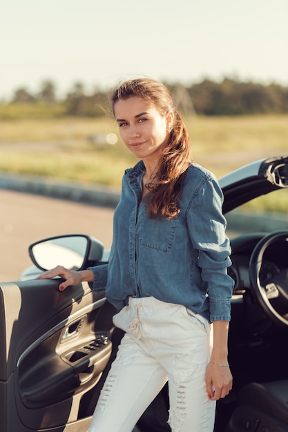 Sexy woman posing next to cabrio car