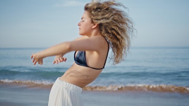 Sexy woman practicing contemporary dance on beautiful ocean shore close up