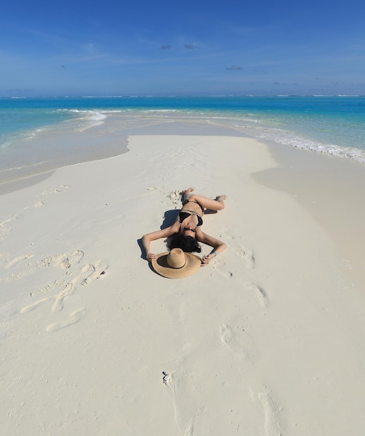 sexy woman in a straw hat lies on the sea sand