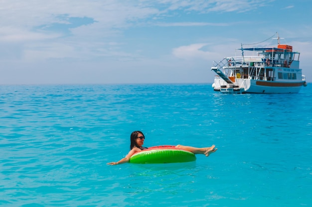 Sexy woman swimming in blue sea on inflatable ring copy space