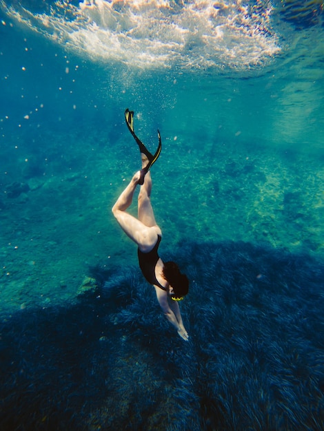 Sexy woman swimming underwater in diving mask with flippers summer vacation