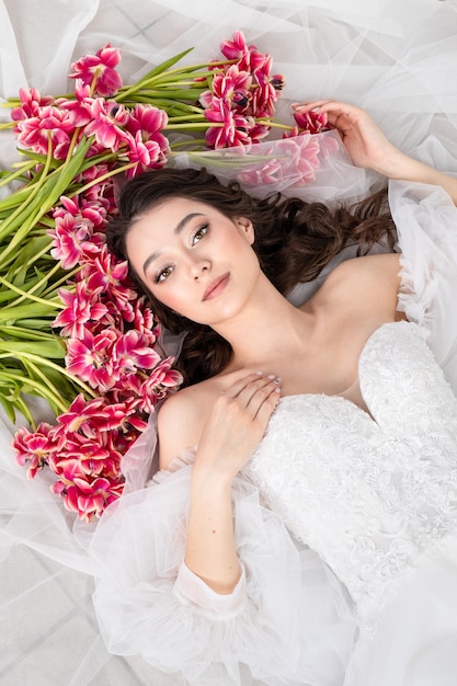 Sexy woman with flowers pink tulips in hands on a light background