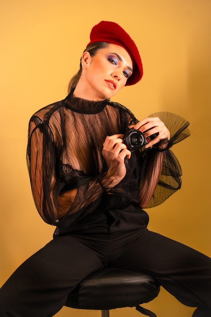 A sexy young female in a red beret and a black transparent shirt holding the camera