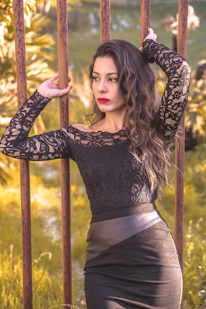 Sexy young woman leaning against a rusty gate in Sicilian countryside