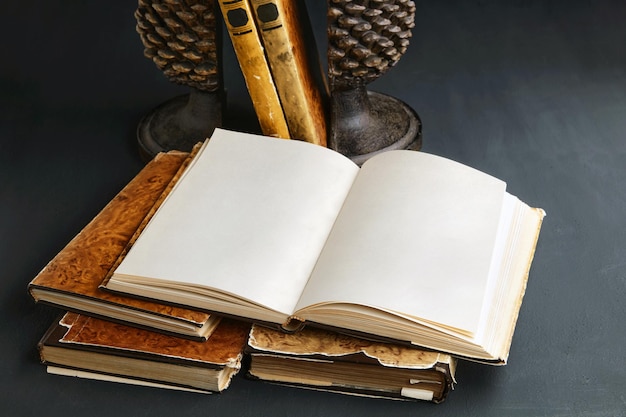 A shabby vintage book with blank pages on a stack of books on a black concrete table