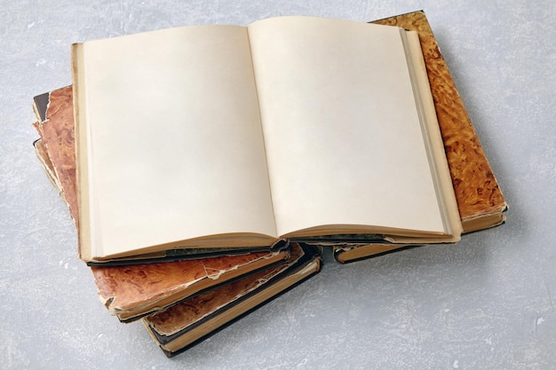 Shabby vintage book with blank pages on a stack of books on a white concrete table