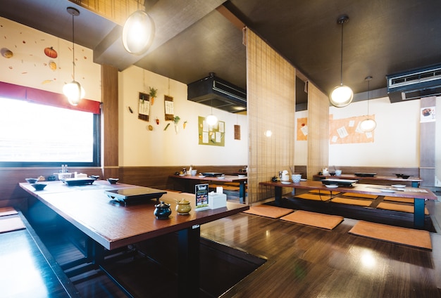 Shabu dining table set including one wooden table and seats on the ground with bamboo ceiling.