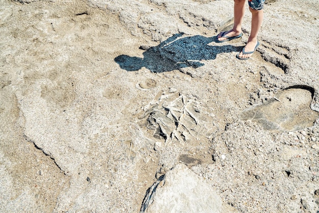 Shadow of male person in shorts cast on rocky beach near sea