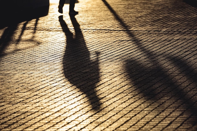 Photo shadow of people walking on footpath