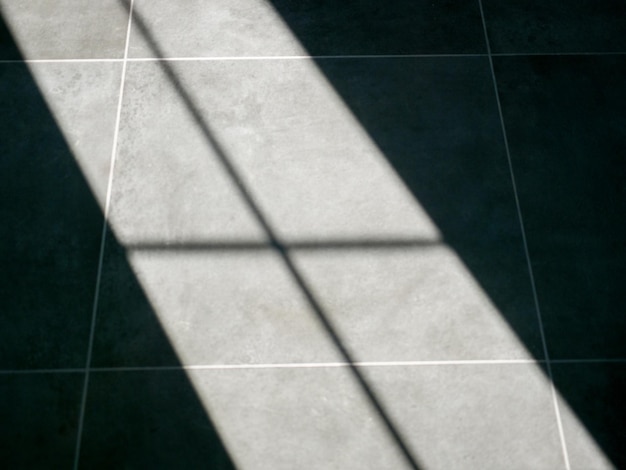 The shadow of the window falling on the floor of gray concrete tiles