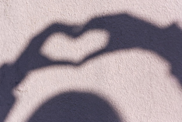 Photo the shadow of a woman on the wall, which shows a heart with her hands. symbol of love