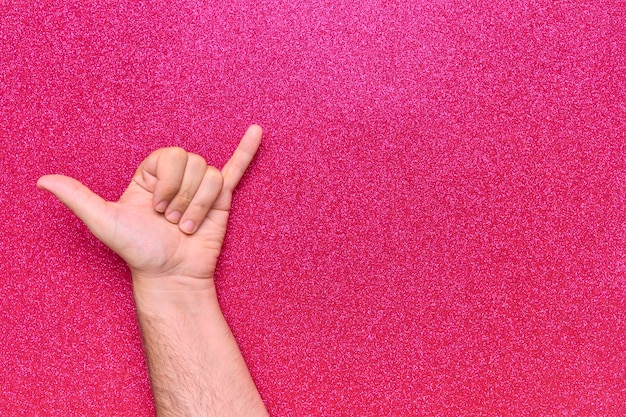 shaka relaxed gesture on man hand with pink glitter background