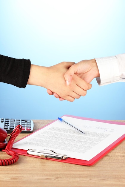 Shaking hands after signing the agreement on a blue background