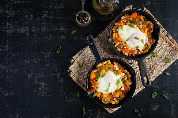 Shakshouka in frying pan Fried eggs with vegetables tomato pepper pumpkin and onion Top view