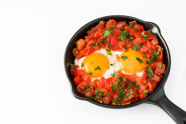 Shakshuka in iron frying pan isolated on white. Typical food in Israel.