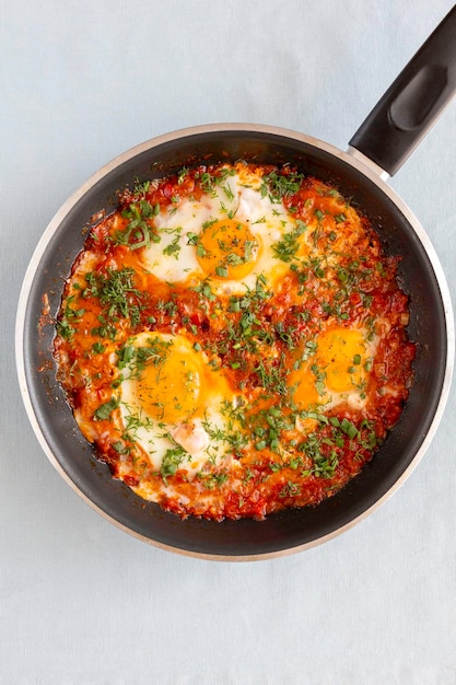 Shakshuka in a pan middle eastern traditional dish fried eggs with tomatoes pepper vegetables and