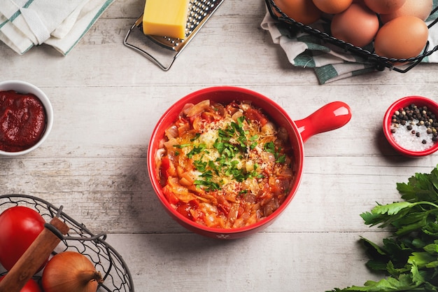 Shakshuka in a red pan on a wooden table.