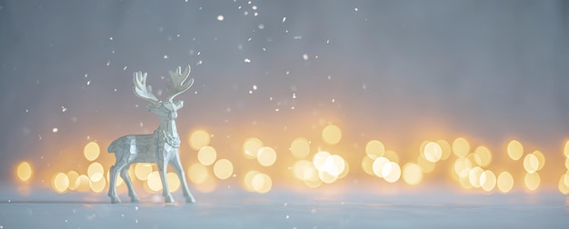 Shallow depth of field image of a Christmas deer figurine in a snowy landscape with bokeh lights