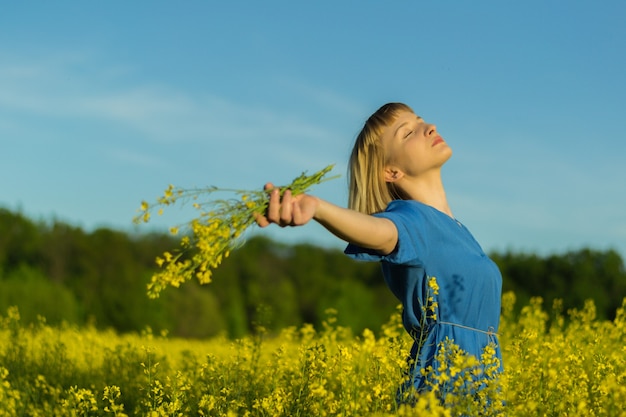 Shallow focus shot of a beautiful caucasian woman wearing a blue dress, posing in a field