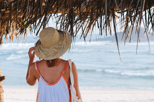 Shallow focus shot of a female wearing a sundress while standing under a shelter by the beach