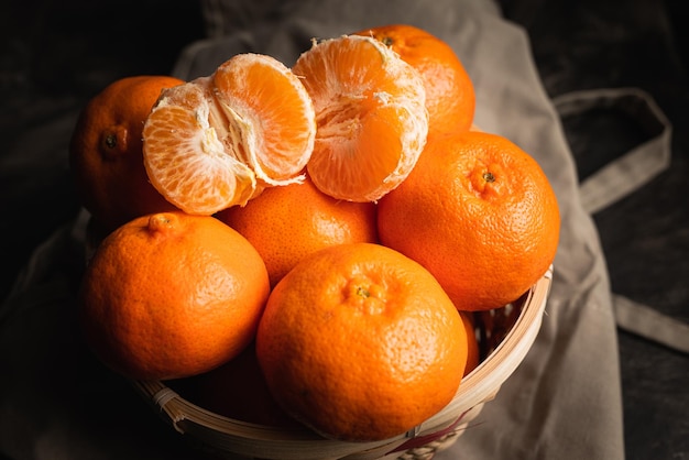 Shallow focus top view of a basket with mandarins on a beige fabric