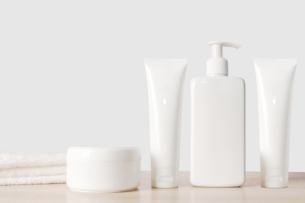 Shampoo cream and white dispenser with white towel On a wooden background