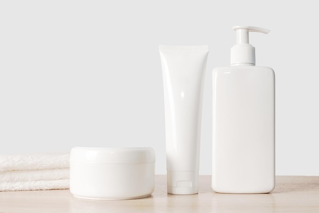 Shampoo cream and white dispenser with white towel On a wooden background