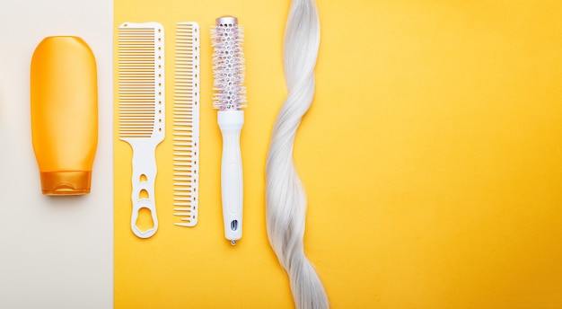 Shampoo, strand lock of blonde hair, different hair combs on color background. Dyed colored hair,hair care, hairdresser haircut beauty salon services. Long web banner with place for text.