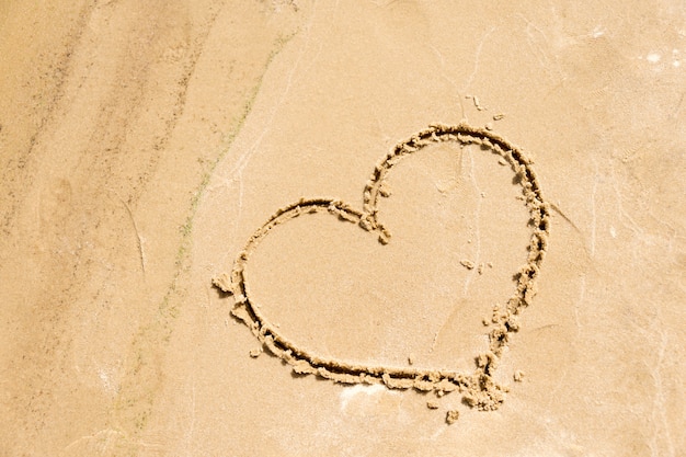 Photo shape of the heart drawn in the sand on the beach