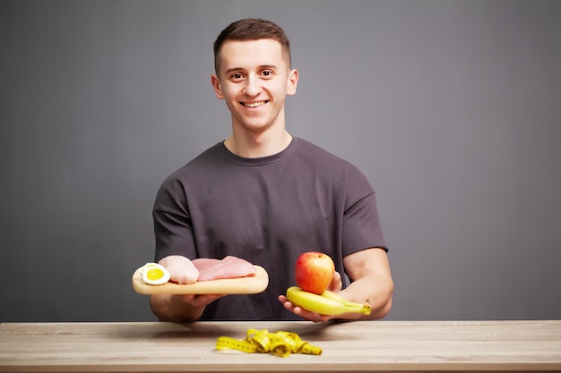 Shaped and healthy man holding a fresh meal board with meat.