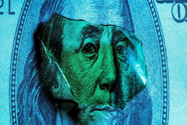 Shards of glass on a portrait of Benjamin Franklin on a dollar bill