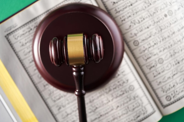 Sharia or Islamic law concept with gavel and koran on green background