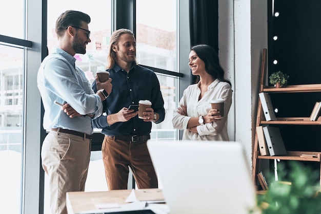 Sharing fresh office news. Young colleagues in smart casual wear discussing something and smiling 