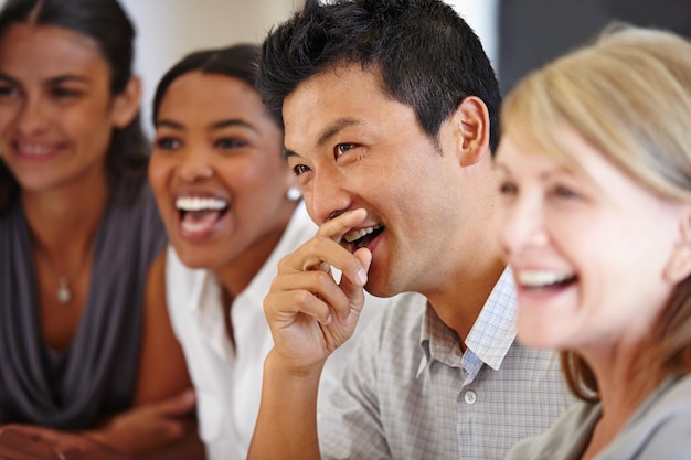 Sharing the joke Shot of an Asian man laughing at a table with his coworkers out of focus