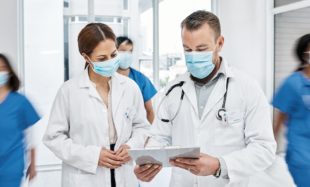 Sharing responsibility in the decision making process Shot of two doctors going through notes in a busy hospital