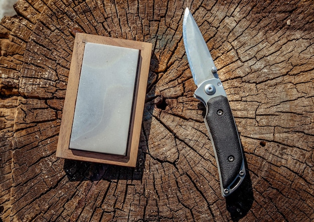 Photo sharp knife and grindstone on a wooden background