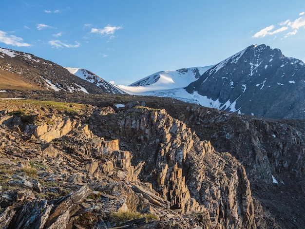 Sharp rocks on the slope Background with a stone slope against a cloudy blue sky Highland scenery with sharpened stones of unusual shape  Scenic mountain landscape with big cracked pointed stones